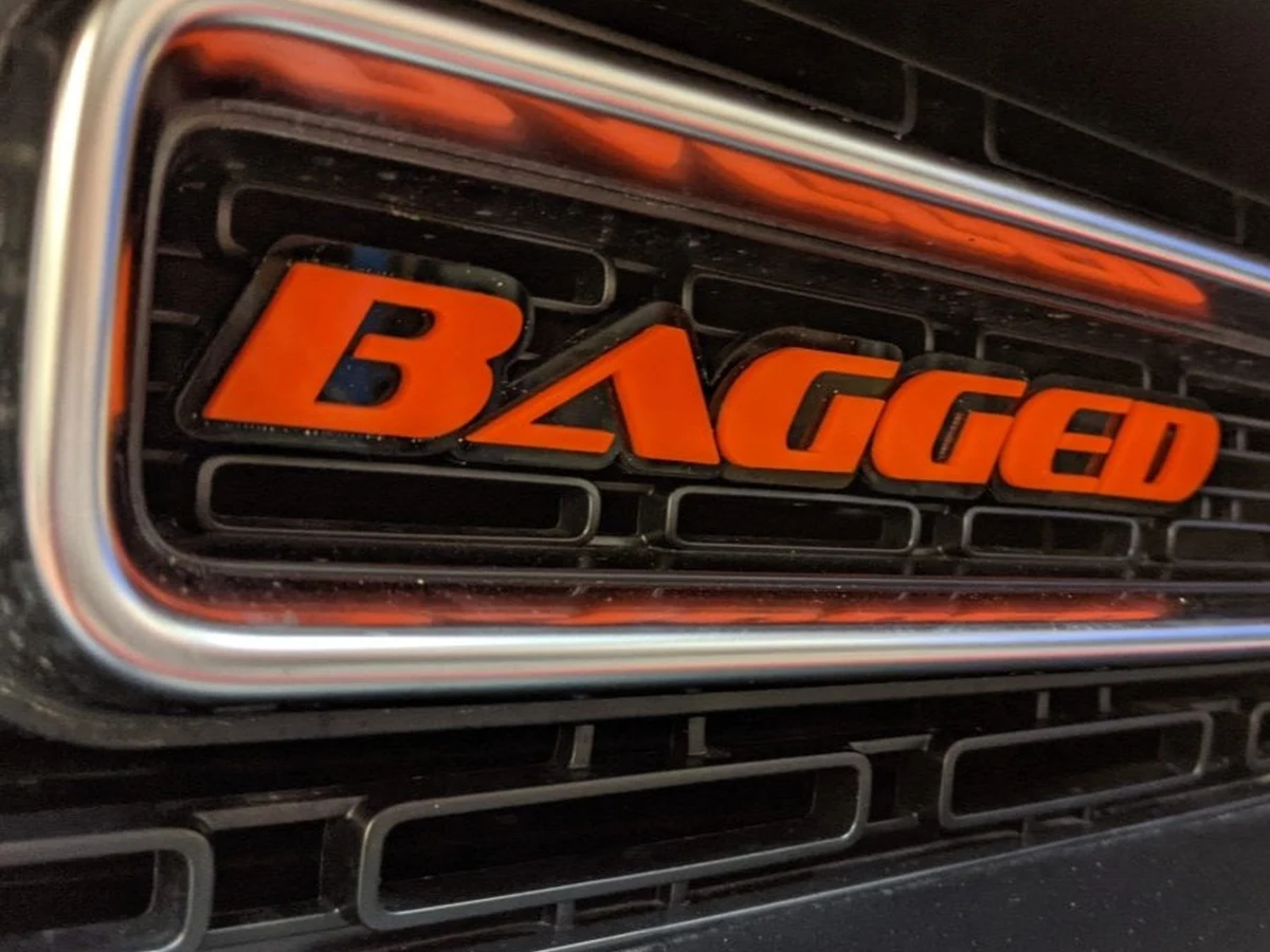 Custom metal text badge installed on a vehicle body panel